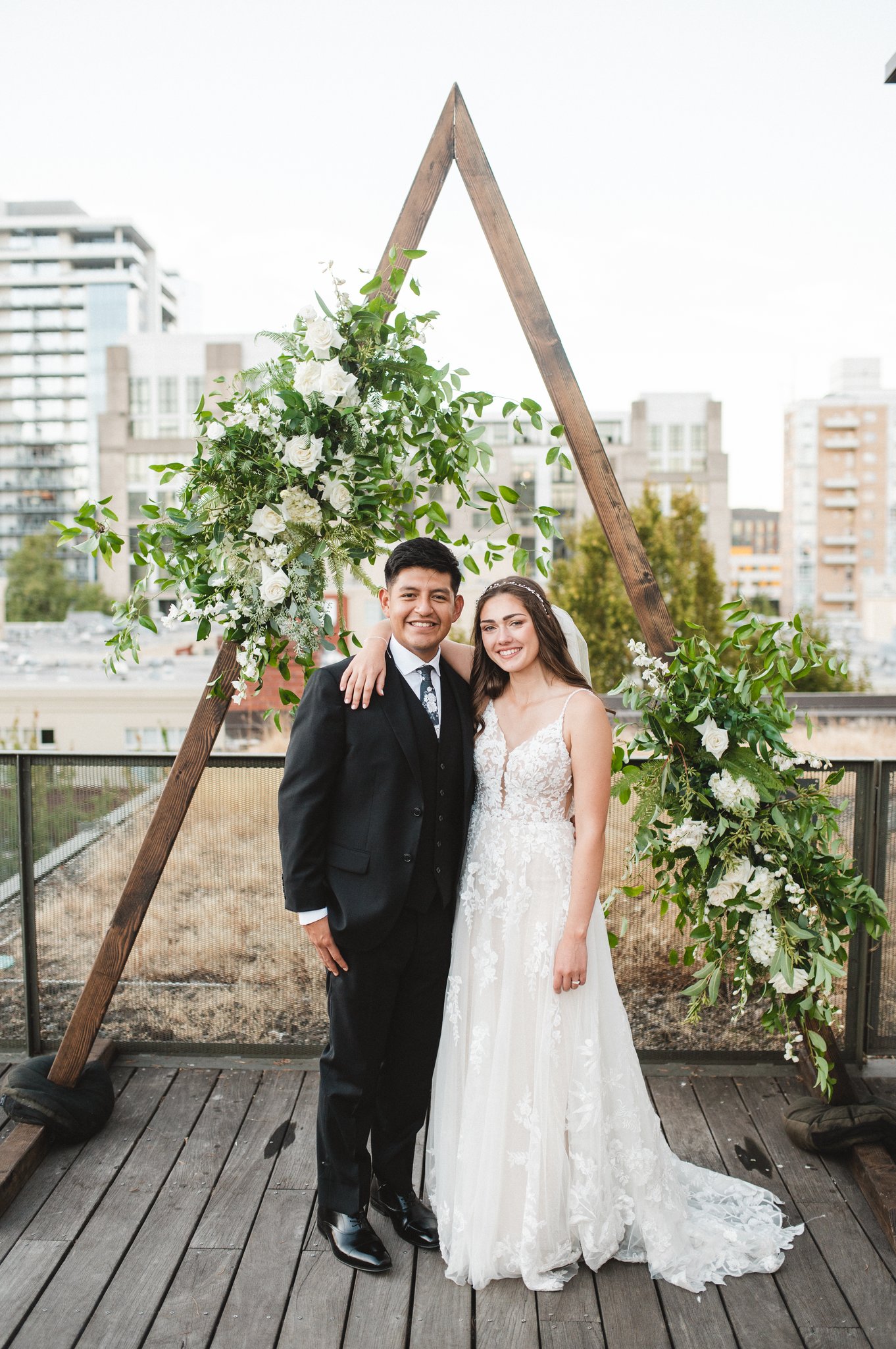 Groom and Bride with beautiful hair posing under floral arch